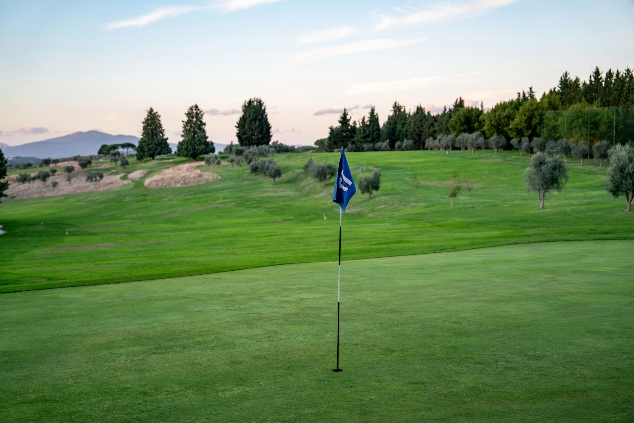 Putting green with flag and rolling fairways